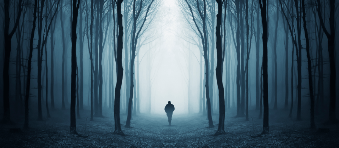 man walking in the dark woods